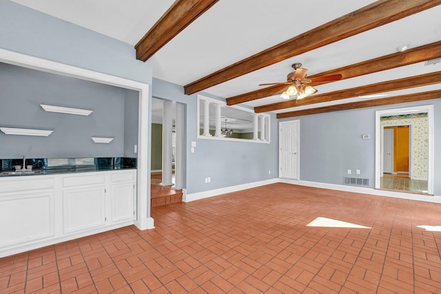 unfurnished living room featuring sink, beamed ceiling, and ceiling fan