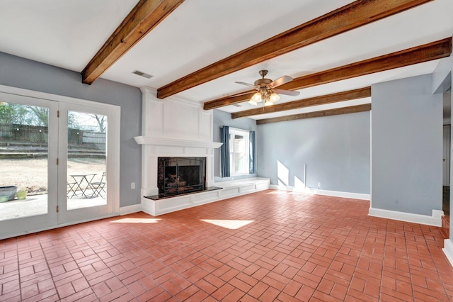 unfurnished living room with ceiling fan, beam ceiling, and a fireplace