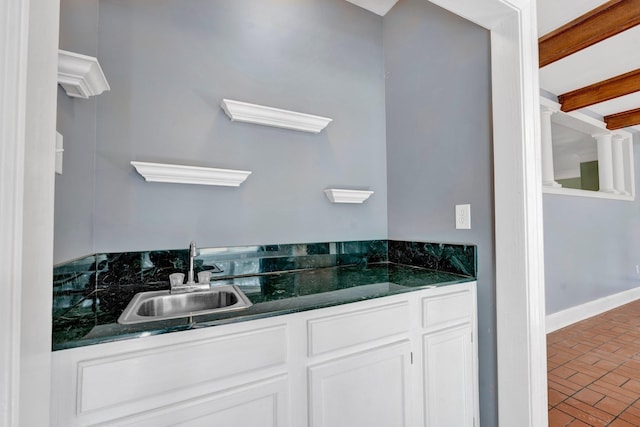 kitchen with sink, white cabinetry, and beamed ceiling