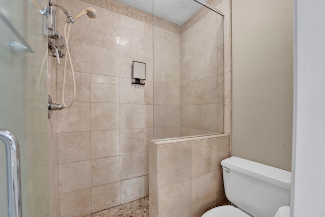 bathroom with a textured ceiling, toilet, and an enclosed shower