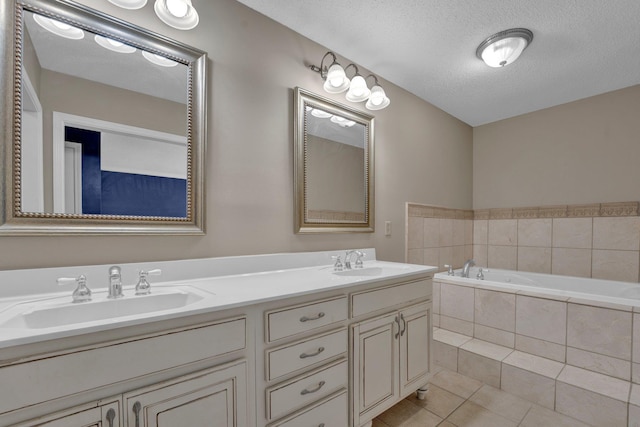 bathroom with tiled bath, a textured ceiling, tile patterned floors, and vanity