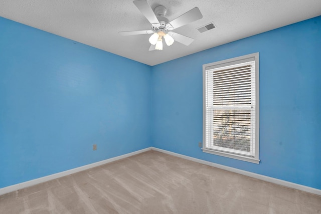 unfurnished room with ceiling fan, a textured ceiling, and light carpet