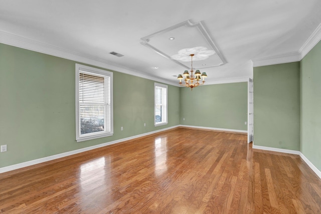 unfurnished room featuring hardwood / wood-style flooring, ornamental molding, and a chandelier