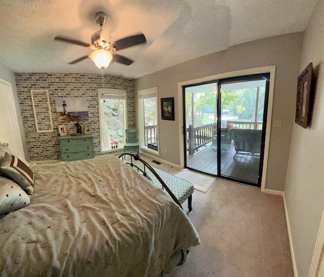 bedroom with brick wall, a textured ceiling, access to exterior, ceiling fan, and light colored carpet