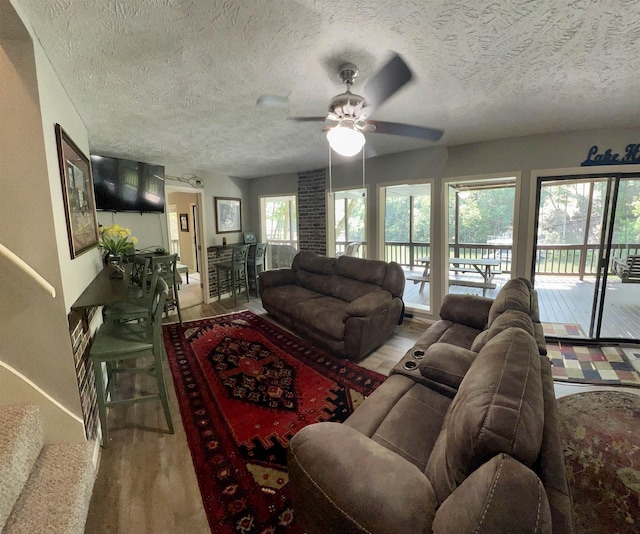 living room featuring hardwood / wood-style flooring, a textured ceiling, and ceiling fan