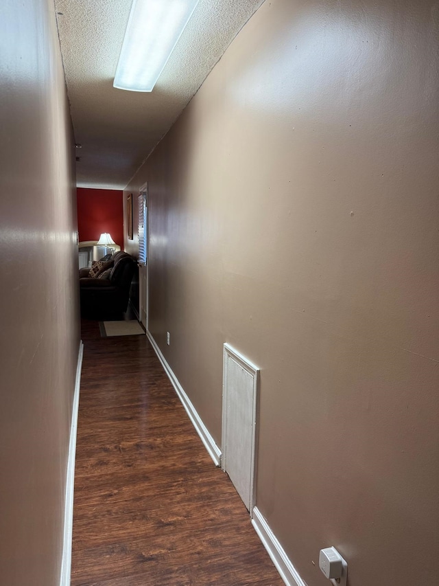 hallway featuring a textured ceiling and dark hardwood / wood-style flooring