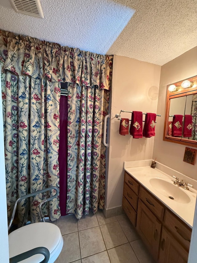 bathroom featuring a textured ceiling, toilet, vanity, and tile patterned flooring