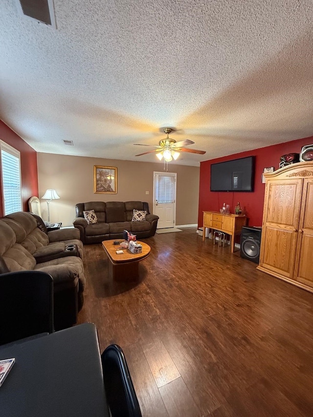 living room with a textured ceiling, ceiling fan, and dark hardwood / wood-style flooring