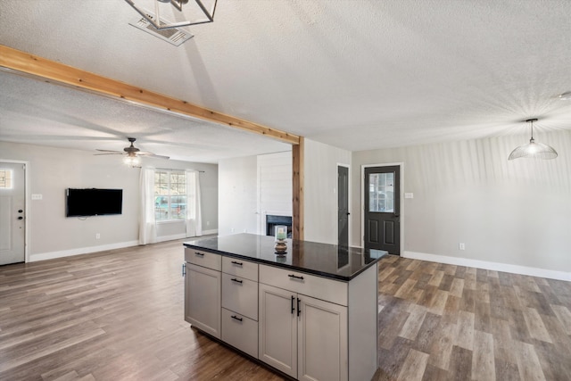 kitchen with decorative light fixtures, light hardwood / wood-style floors, a center island, and a textured ceiling