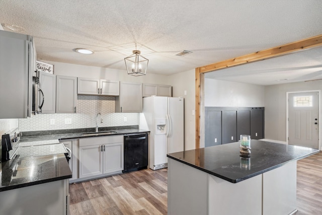 kitchen with white refrigerator with ice dispenser, sink, gray cabinetry, black dishwasher, and a kitchen island