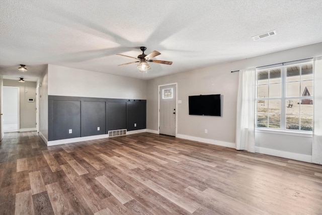 unfurnished living room featuring hardwood / wood-style flooring, ceiling fan, and a textured ceiling