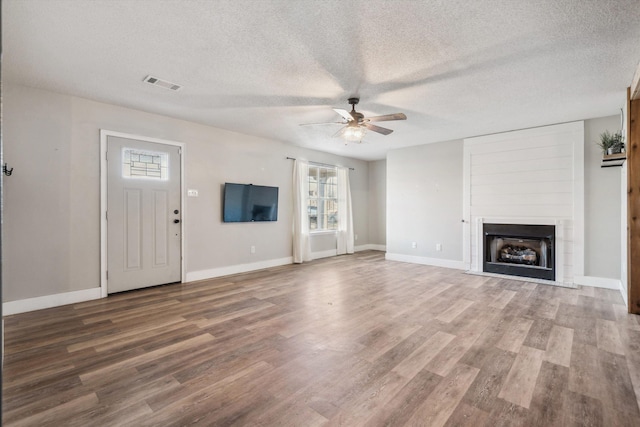 unfurnished living room with a fireplace, wood-type flooring, a textured ceiling, and a wealth of natural light