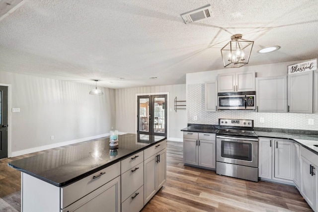 kitchen with gray cabinets, backsplash, hanging light fixtures, and stainless steel appliances