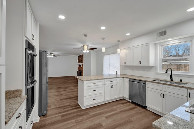 kitchen featuring a fireplace, visible vents, appliances with stainless steel finishes, a sink, and a peninsula