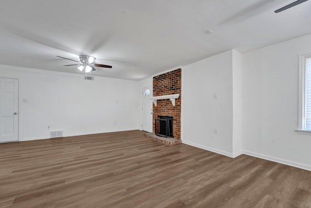 unfurnished living room featuring hardwood / wood-style flooring, a brick fireplace, and ceiling fan