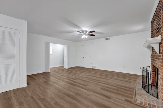 unfurnished living room with a brick fireplace, visible vents, and wood finished floors