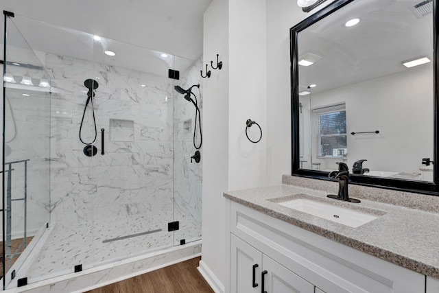 bathroom featuring a marble finish shower, recessed lighting, visible vents, vanity, and wood finished floors