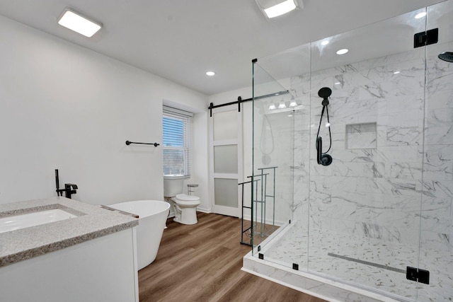 full bath with a freestanding tub, a stall shower, wood finished floors, and vanity