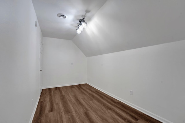 additional living space with vaulted ceiling, dark wood-style floors, visible vents, and baseboards