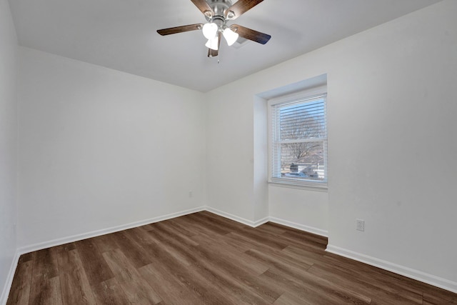 spare room featuring a ceiling fan, baseboards, and dark wood-type flooring