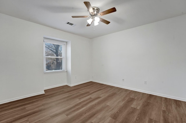 unfurnished room featuring baseboards, visible vents, ceiling fan, and wood finished floors