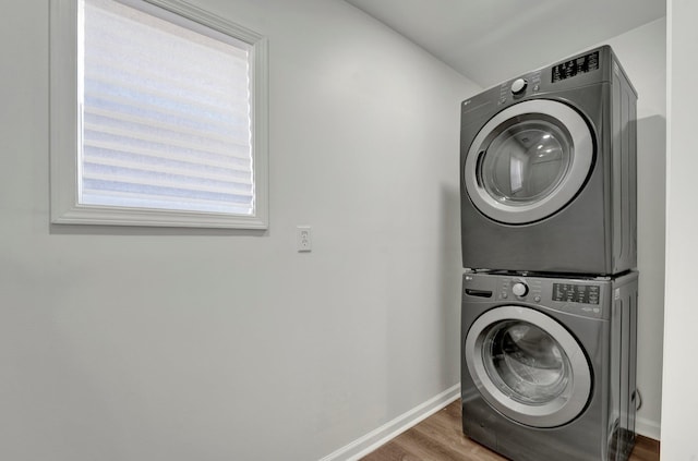 laundry area with dark hardwood / wood-style floors and stacked washer and clothes dryer