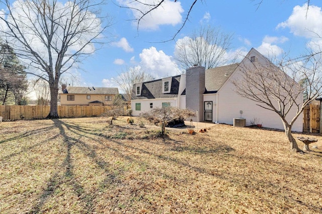 back of property featuring central AC unit and a lawn