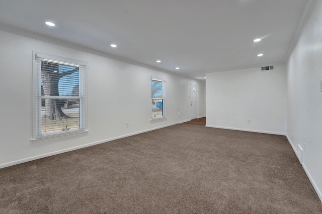 spare room featuring ornamental molding and dark colored carpet