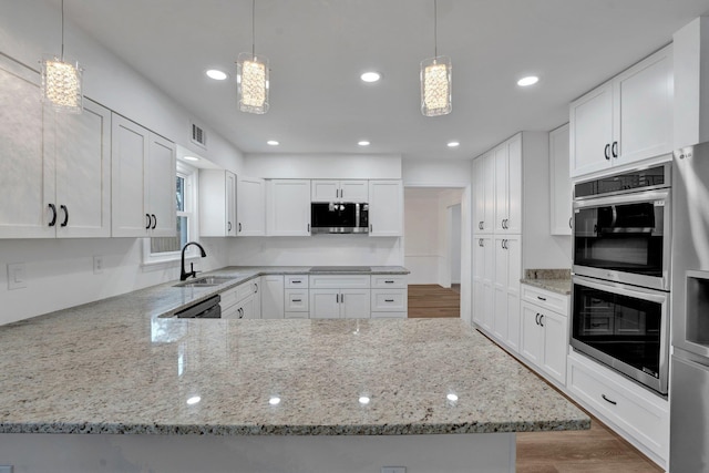 kitchen featuring sink, black appliances, white cabinetry, and hanging light fixtures