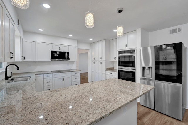 kitchen with appliances with stainless steel finishes, white cabinetry, sink, kitchen peninsula, and pendant lighting