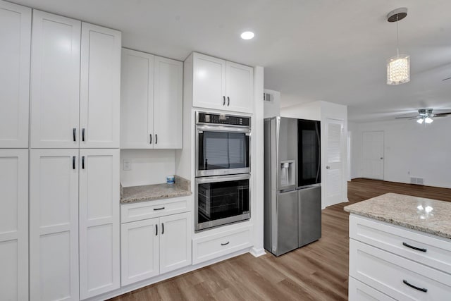 kitchen with light stone counters, visible vents, white cabinetry, appliances with stainless steel finishes, and light wood finished floors