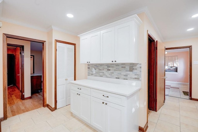 interior space featuring white cabinets, ornamental molding, light tile patterned floors, and tasteful backsplash