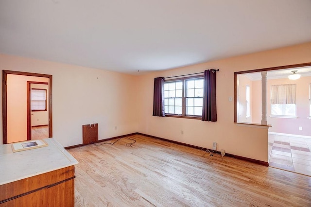 unfurnished living room with ornate columns and light hardwood / wood-style floors