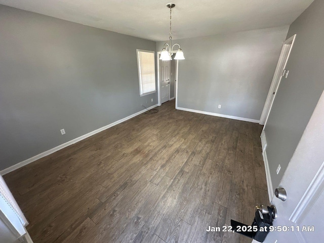 unfurnished dining area with dark wood-type flooring and a notable chandelier