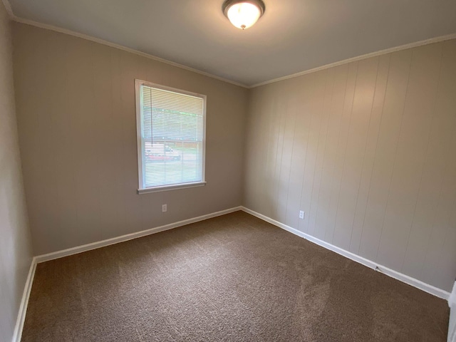 spare room with ornamental molding and dark colored carpet