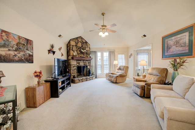 carpeted living room with ceiling fan, a stone fireplace, and lofted ceiling