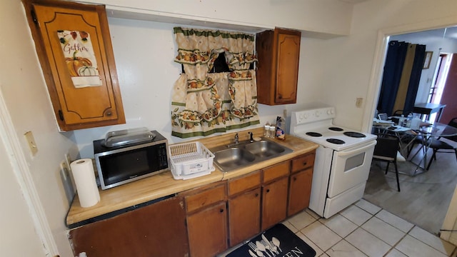 kitchen featuring electric stove, sink, and light tile patterned flooring