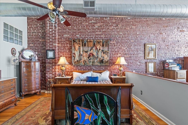 bedroom with ceiling fan, brick wall, and hardwood / wood-style floors