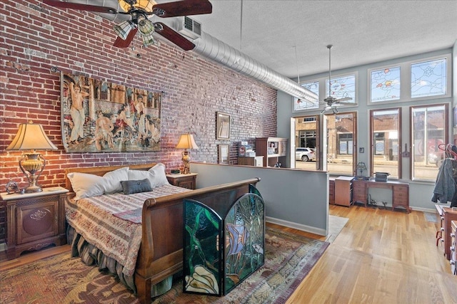 bedroom featuring multiple windows, brick wall, a textured ceiling, and a towering ceiling