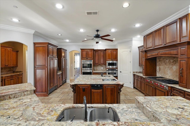 kitchen with sink, appliances with stainless steel finishes, a kitchen island with sink, and tasteful backsplash