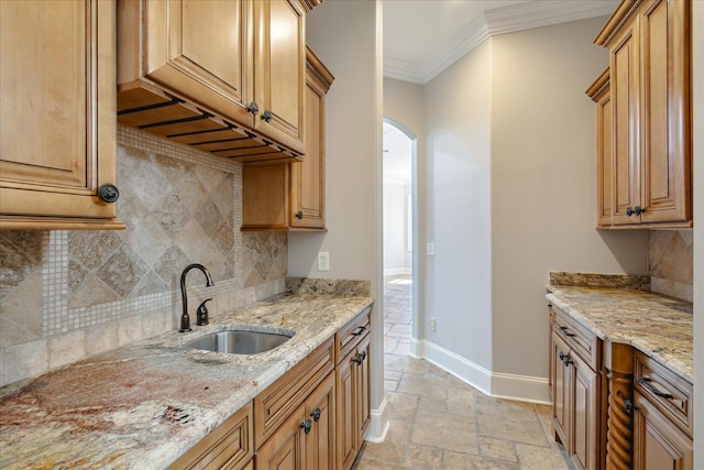 kitchen featuring sink, backsplash, light stone countertops, and ornamental molding