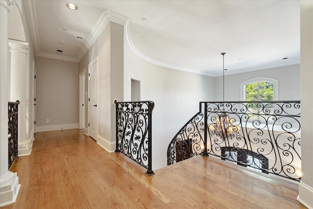 hallway featuring crown molding, decorative columns, and light wood-type flooring