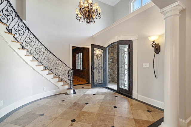 entrance foyer featuring a notable chandelier, a towering ceiling, french doors, and ornate columns