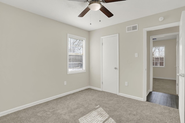 unfurnished bedroom with ceiling fan, multiple windows, and carpet flooring