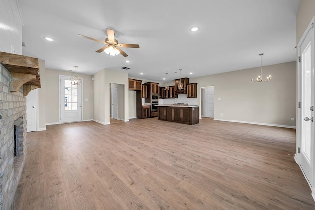 unfurnished living room with a fireplace, light hardwood / wood-style floors, and ceiling fan with notable chandelier