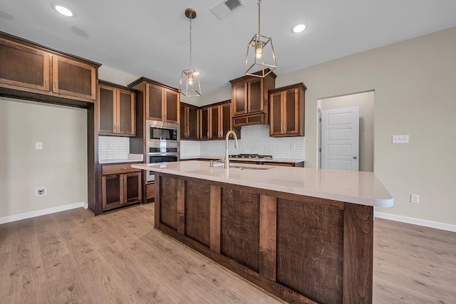 kitchen featuring tasteful backsplash, sink, light hardwood / wood-style flooring, pendant lighting, and stainless steel appliances