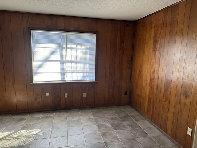 empty room featuring wood walls and a textured ceiling