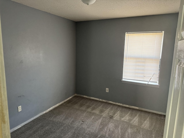 unfurnished room with a textured ceiling and dark carpet