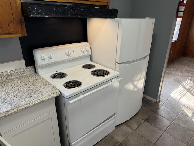 kitchen with light tile patterned flooring, white appliances, extractor fan, and light stone counters