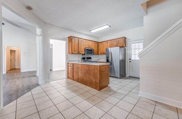 kitchen with decorative backsplash, appliances with stainless steel finishes, and light tile patterned flooring